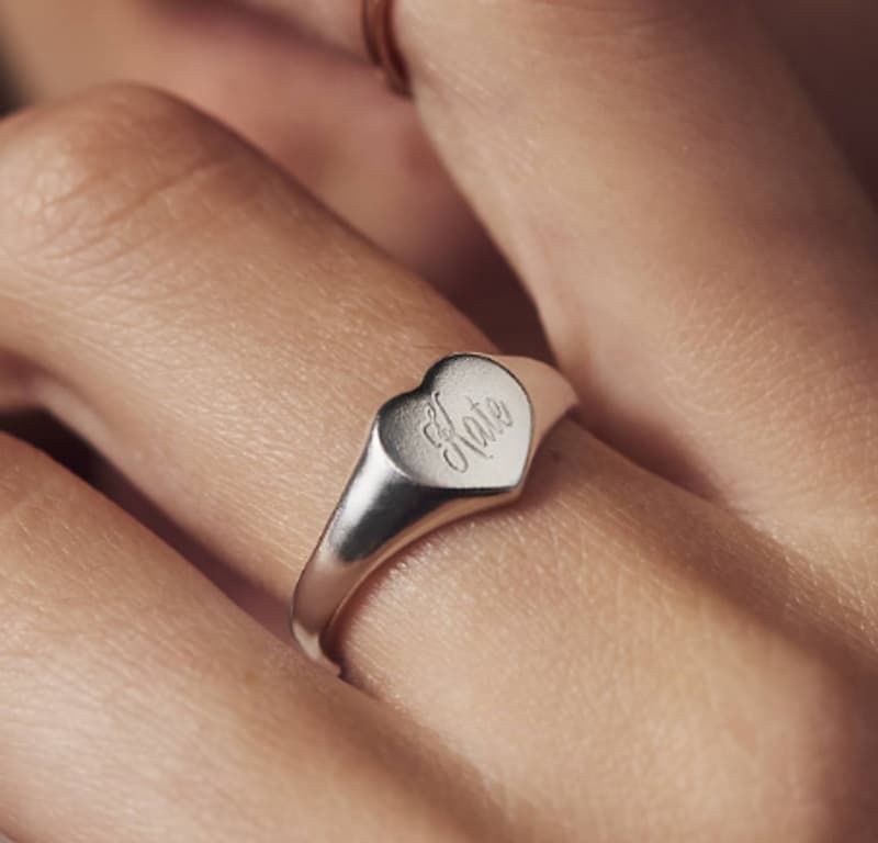 Hand-engraved script lettering on a heart signet ring